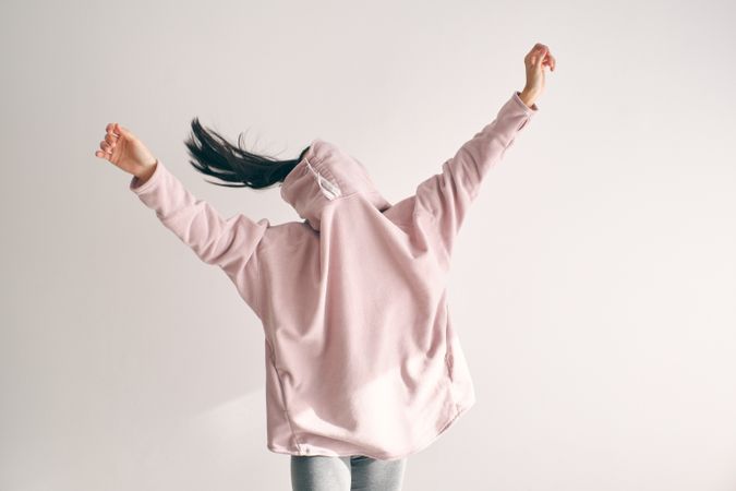 Energetic woman in baggy sweater raising hands up