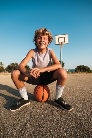 Cheerful boy with basketball on sports ground