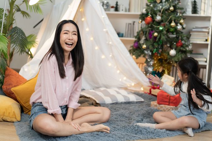 Asian mother laughing and playing with daughter at cozy tent