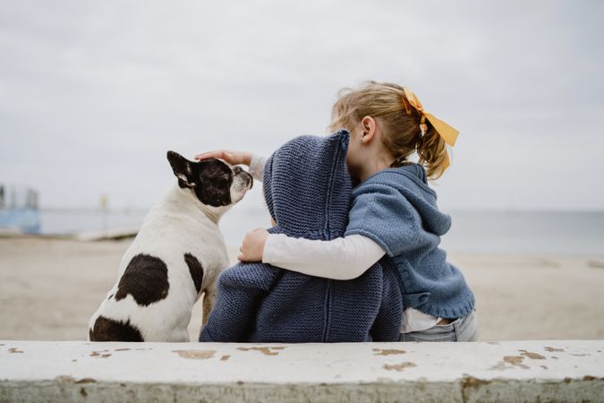 Kids hugging dog on beach
