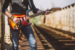 anonymous Man with guitar standing on bridge