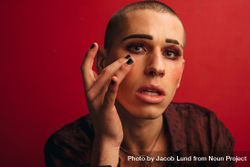 Male putting makeup on against red background 5wmAAb