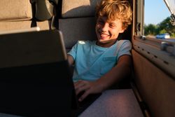 Funny boy using laptop in caravan