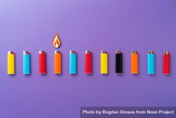 Colorful lighters in a row on purple background 0gzo8b