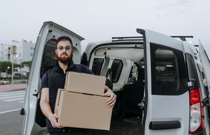 Courier taking out cartons of car for delivery completion