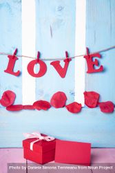 Red gift box with blank message card and the word love written in paper letters hanging on twine 0vmEGb