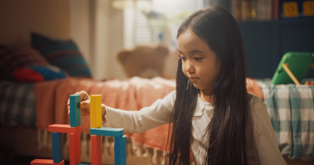 Portrait of Focused Little Girl Playing with Construction Building Blocks while in Children's Room.