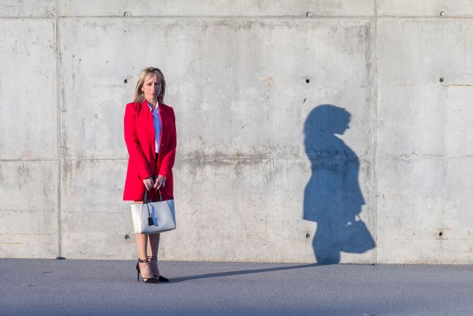 Woman standing in front of cement wall with long shadow