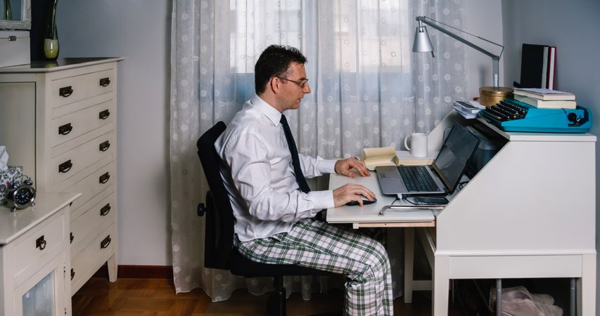 Man teleworking wearing shirt, tie and pajama pants