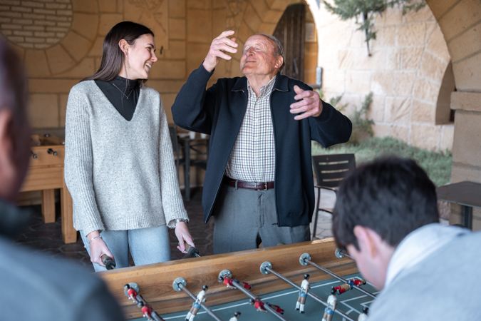 A granddaugther and grandfather are having fun after being scored in table football