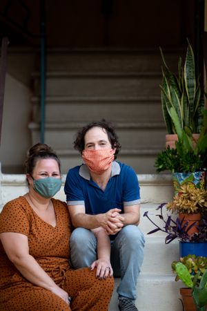 Portrait of happy couple sitting on outside stairs with plants
