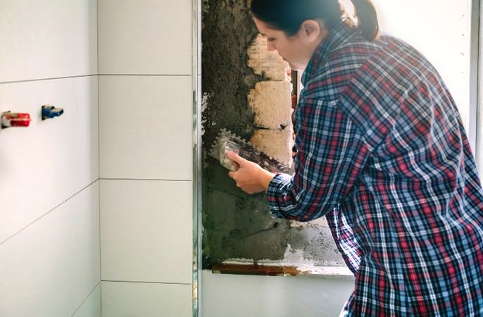 Female mason leveling cement with a trowel