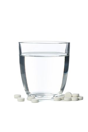 Full water glass surrounded by pills in blank background
