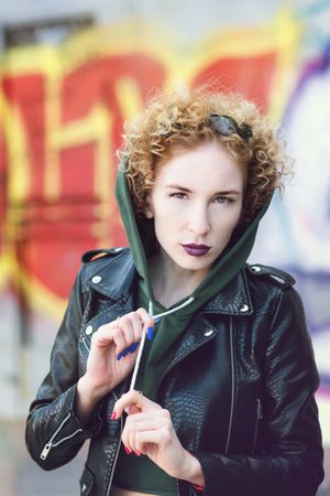 Fashionable portrait young woman hipster in green sweatshirt and leather biker jacket