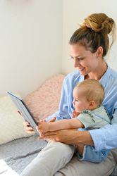 Smiling mother and baby watching movie on tablet together