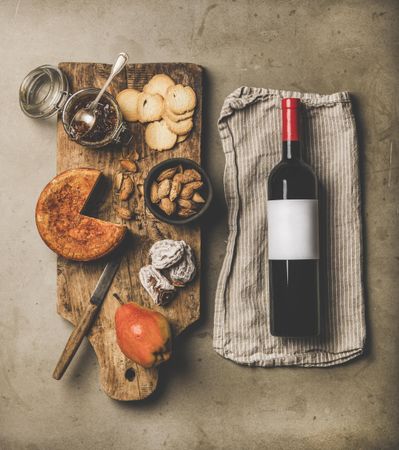 Cheese plate with red bottle of wine, on linen towel, square crop