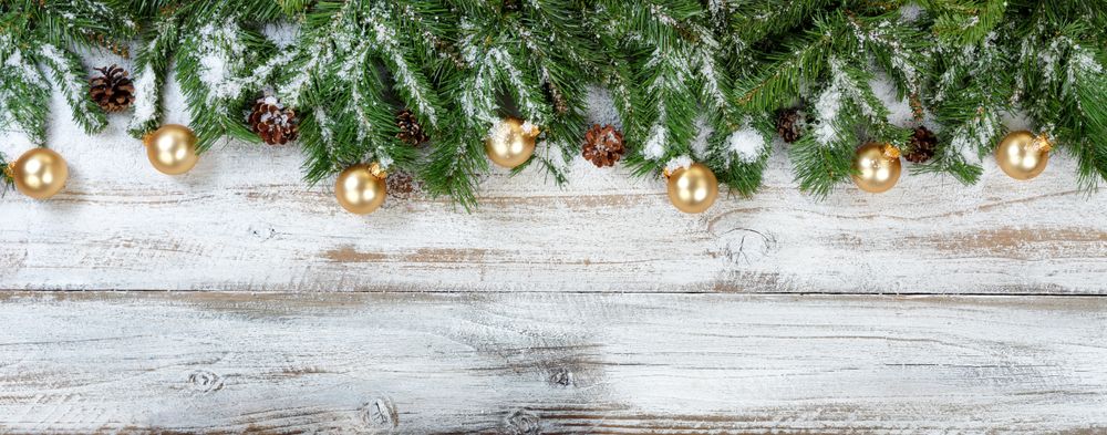 Christmas branches and golden ornaments with snow on rustic wooden background