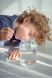 Sad boy putting small fishing rod in glass bottle of water