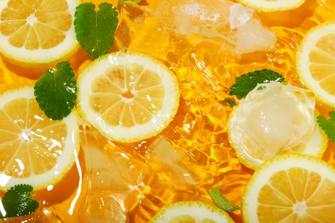 Lemon slices floating in water with mint slices and ice
