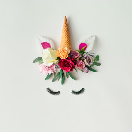 Unicorn head with colorful flowers, leaves and ice cream cone on light background