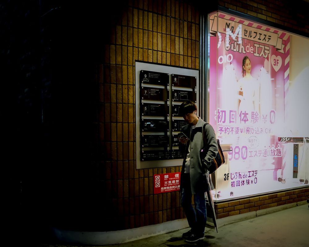 Young man standing on sidewalk at night