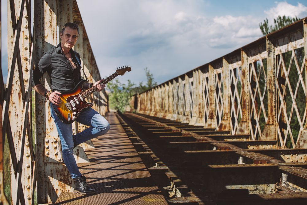 Man with guitar standing on bridge