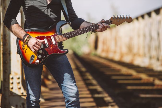 anonymous Man with guitar standing on bridge