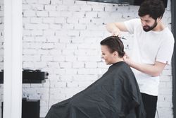 Hairdresser cuts woman's hair with scissors