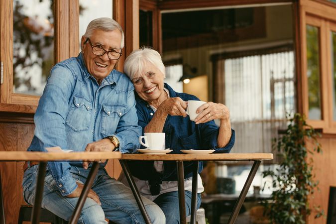 Beautiful portrait of a man and woman sitting at cafe table with coffee looking at camera