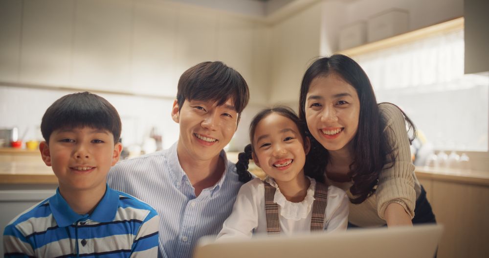Portrait of Happy Korean Family Using Laptop Computer then Looking at the Camera and Smiling.