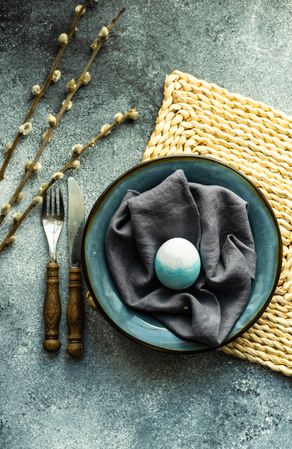 Top view of Easter holiday table setting with blue Easter egg in bowl