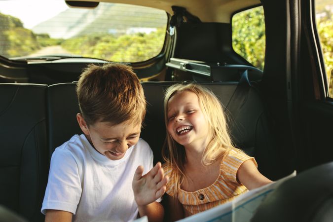 Kids traveling in a car on roadtrip playing with a map