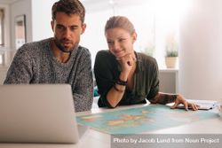 Young man and woman looking at laptop computer with world map in front 56xXzb