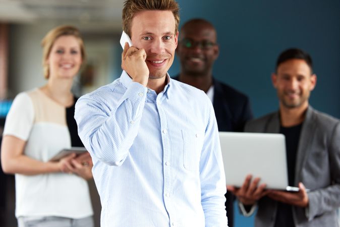 Businessman on cellphone in front of colleagues