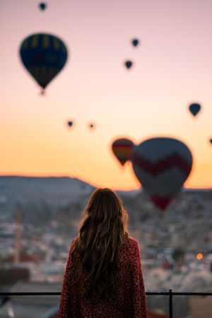 Back view of woman watching the parachutes scene in Cappadocia, Central Anatolia, Turkey