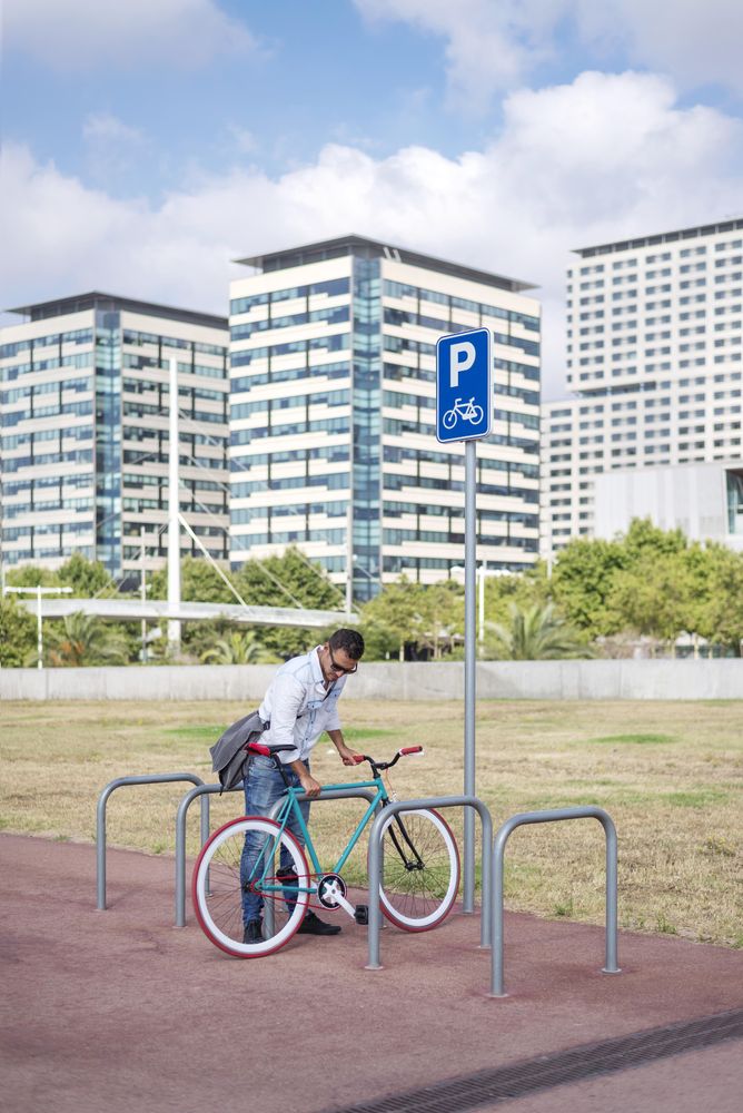 Male with colorful bicycle parking at rack in city