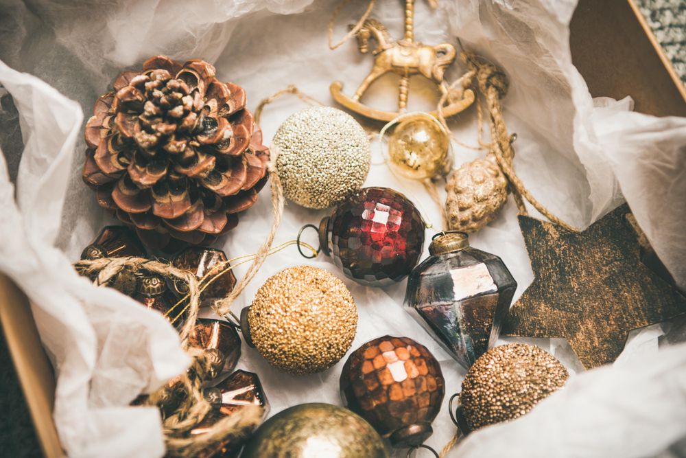 Wooden box of rustic holiday tree decorations, pine cones, baubles, laying on tissue paper, close up