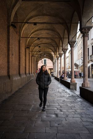 Asian female on vacation in warm clothing walking on old streets of city