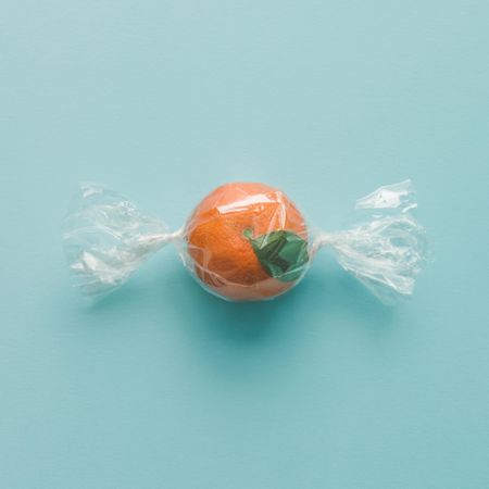 Orange wrapped like candy on bright blue background