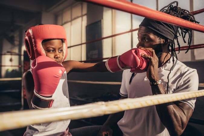 Student practicing punches wearing boxing gloves and headgear with her coach