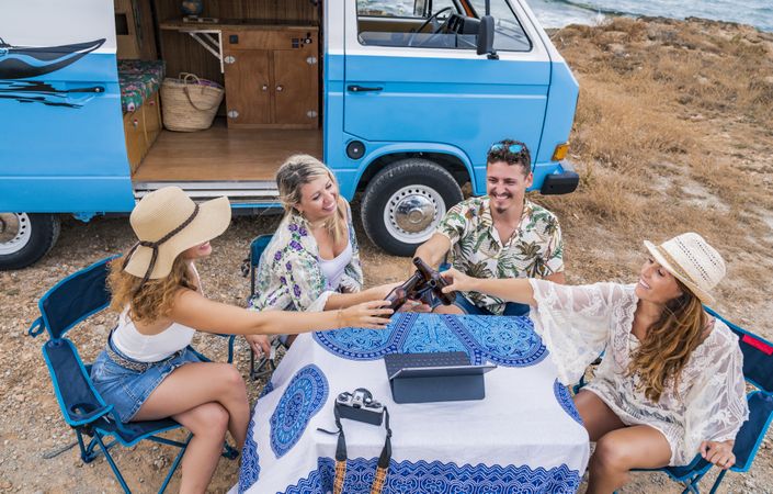 Smiling friends clinking bottles of beer celebrating vacation
