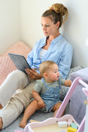 Calm woman using tablet while spending time with child