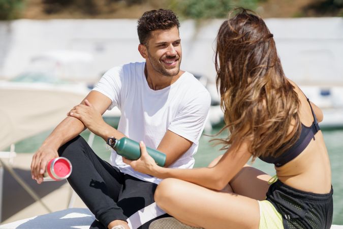 Man and woman talking on pier on sunny day