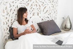 Woman sitting in bed with laptop and cup of coffee 41QpD4