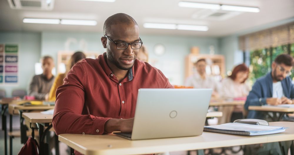 Adult Education Center: Black Student Learning in Classroom, Using Laptop to Write Down Notes.
