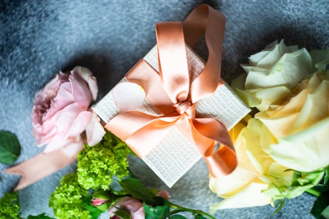 Top view with pastel flowers on grey counter with present