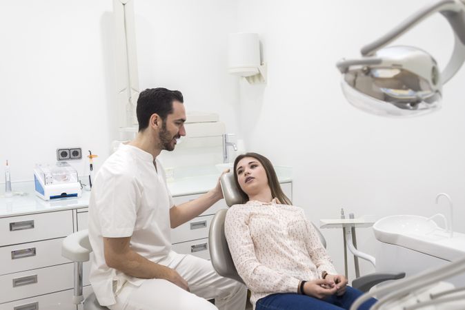 Portrait of a bearded dentist male explaining procedure to a female patient