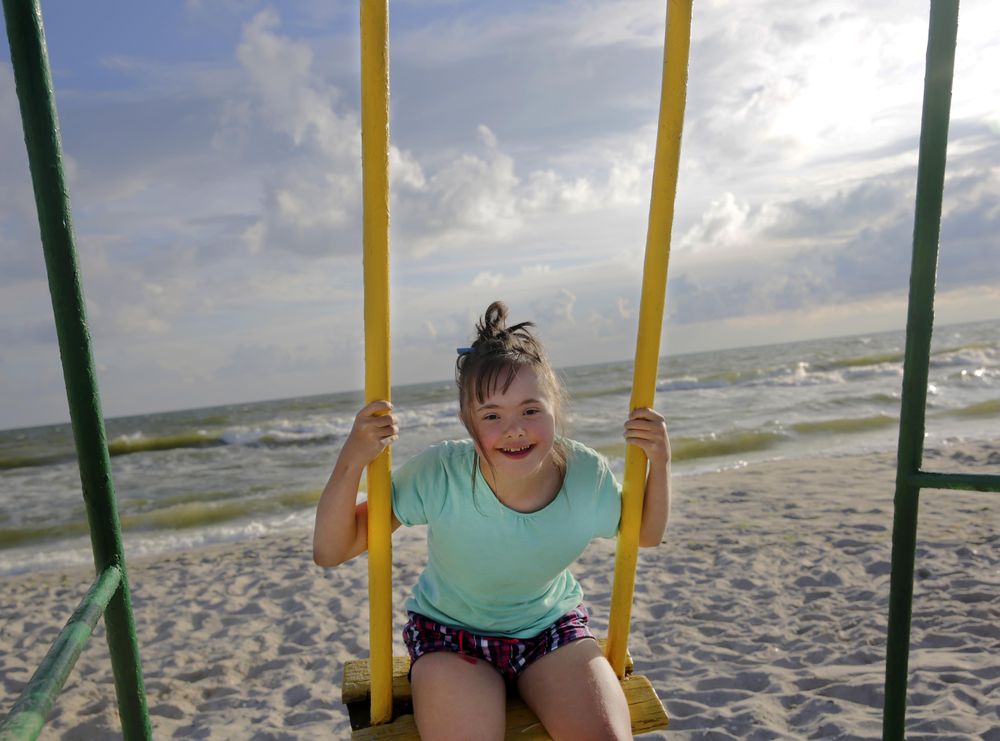 Smiling girl having fun on swing set at beach