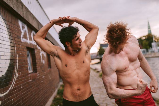 Shot of two young men having fun and flexing their muscles outdoors