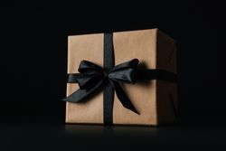 Gift box with dark bow on dark background